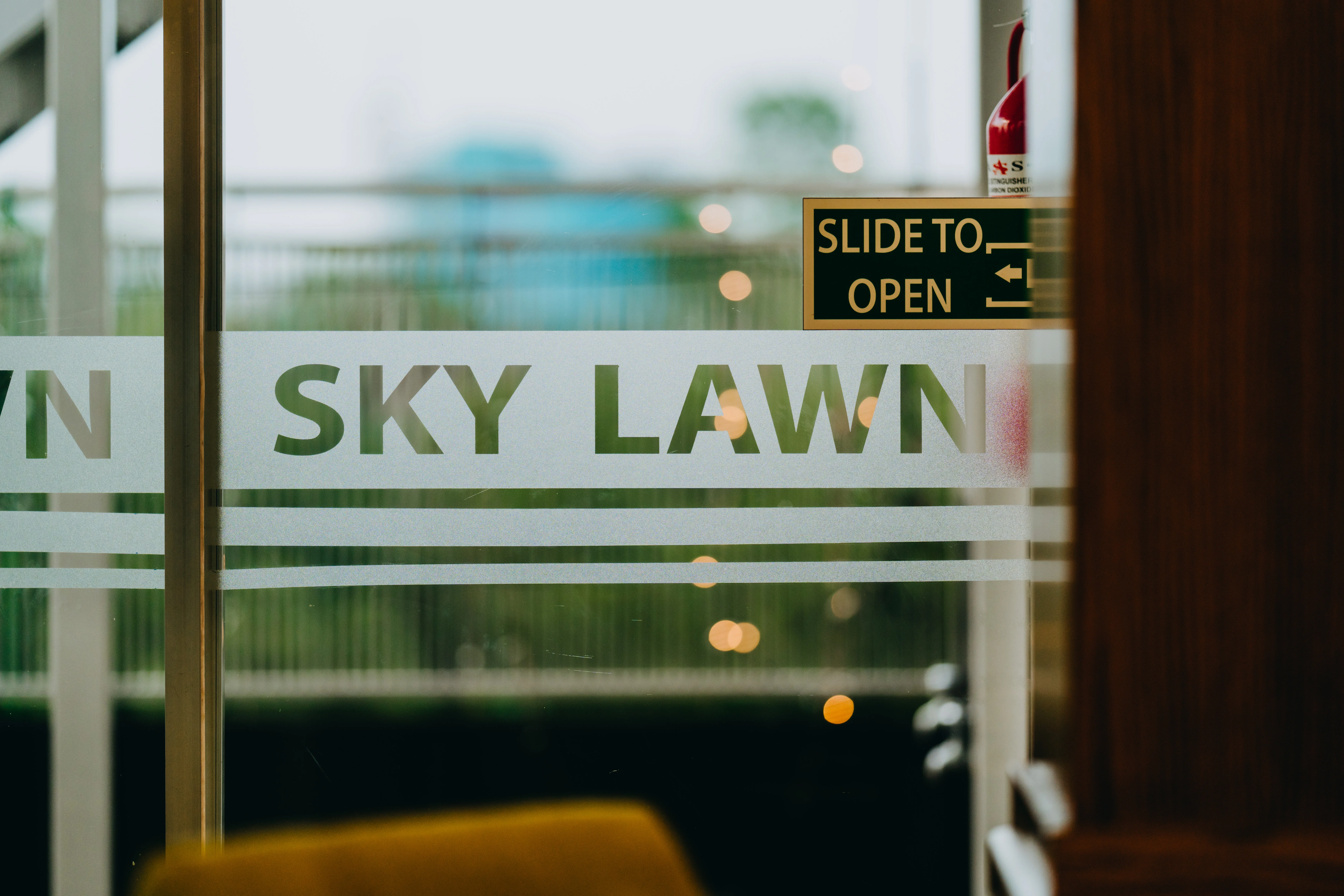 Sky Lawn Hotel's guest room features a modern workspace with a glass-top desk, wooden chair, wall...