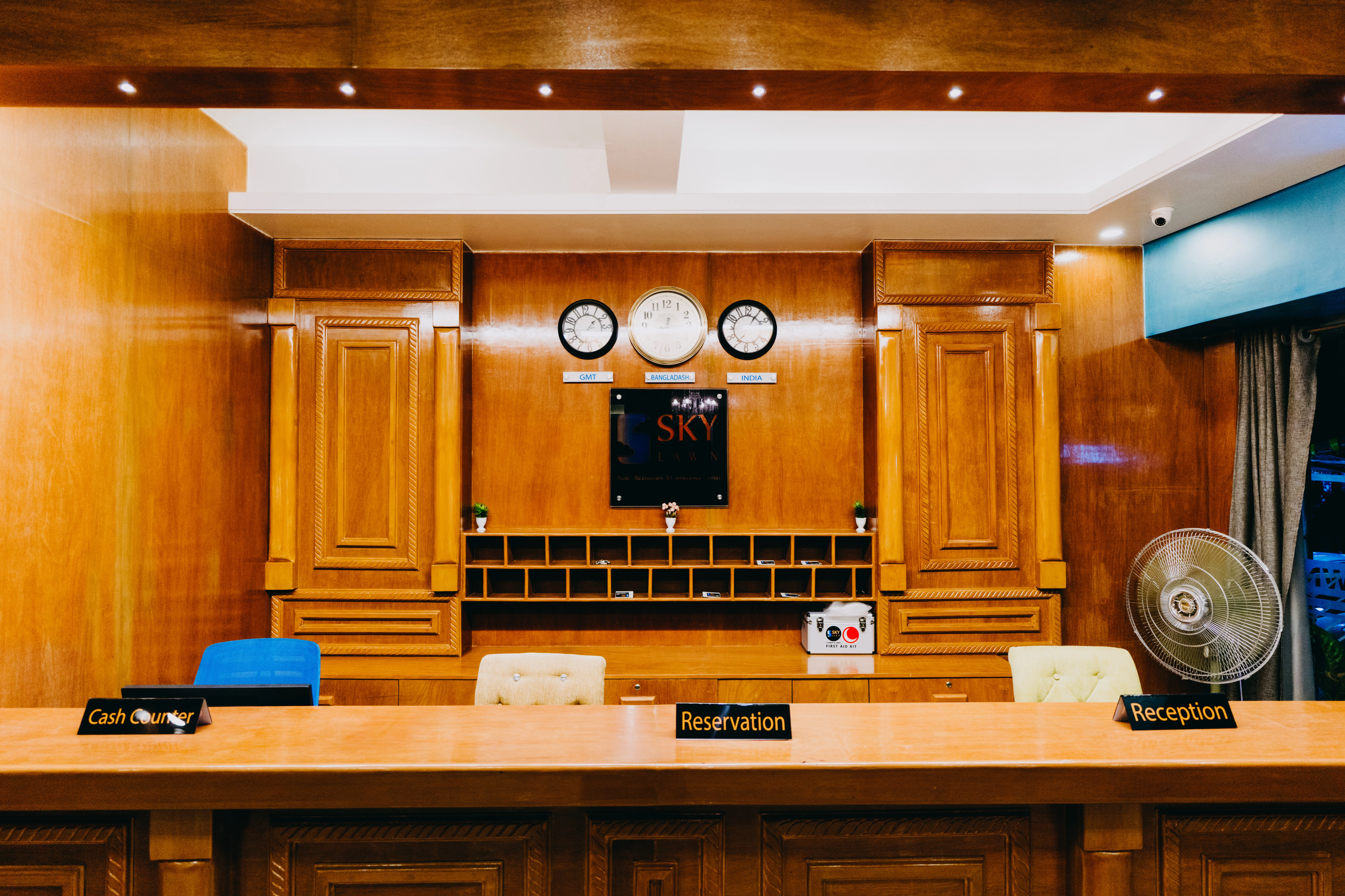 This image showcases the **Sky Lawn Hotel reception area**, featuring a polished wooden front des...