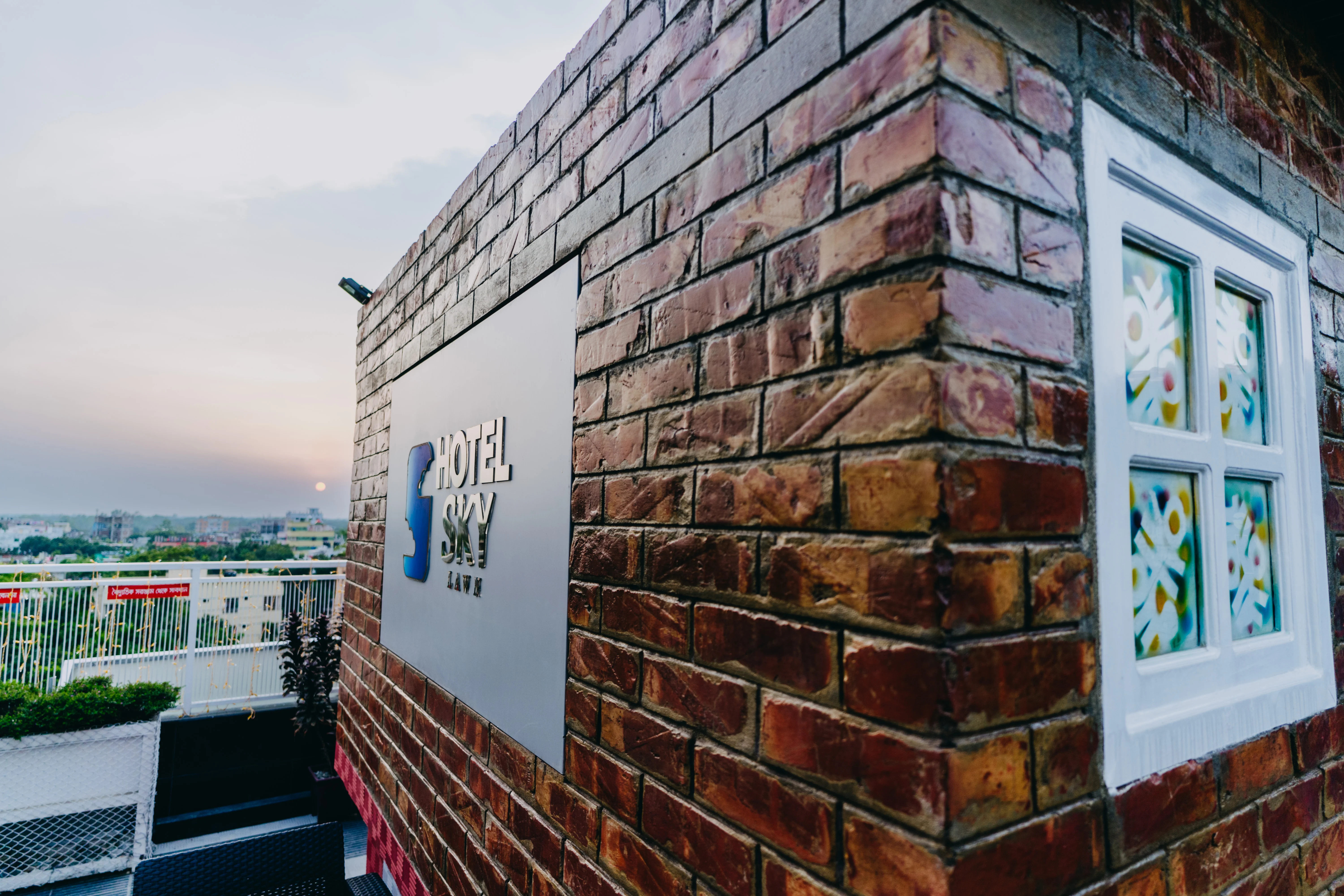 Sky Lawn Hotel’s rooftop terrace features a textured red brick wall, white-framed stained glass w...