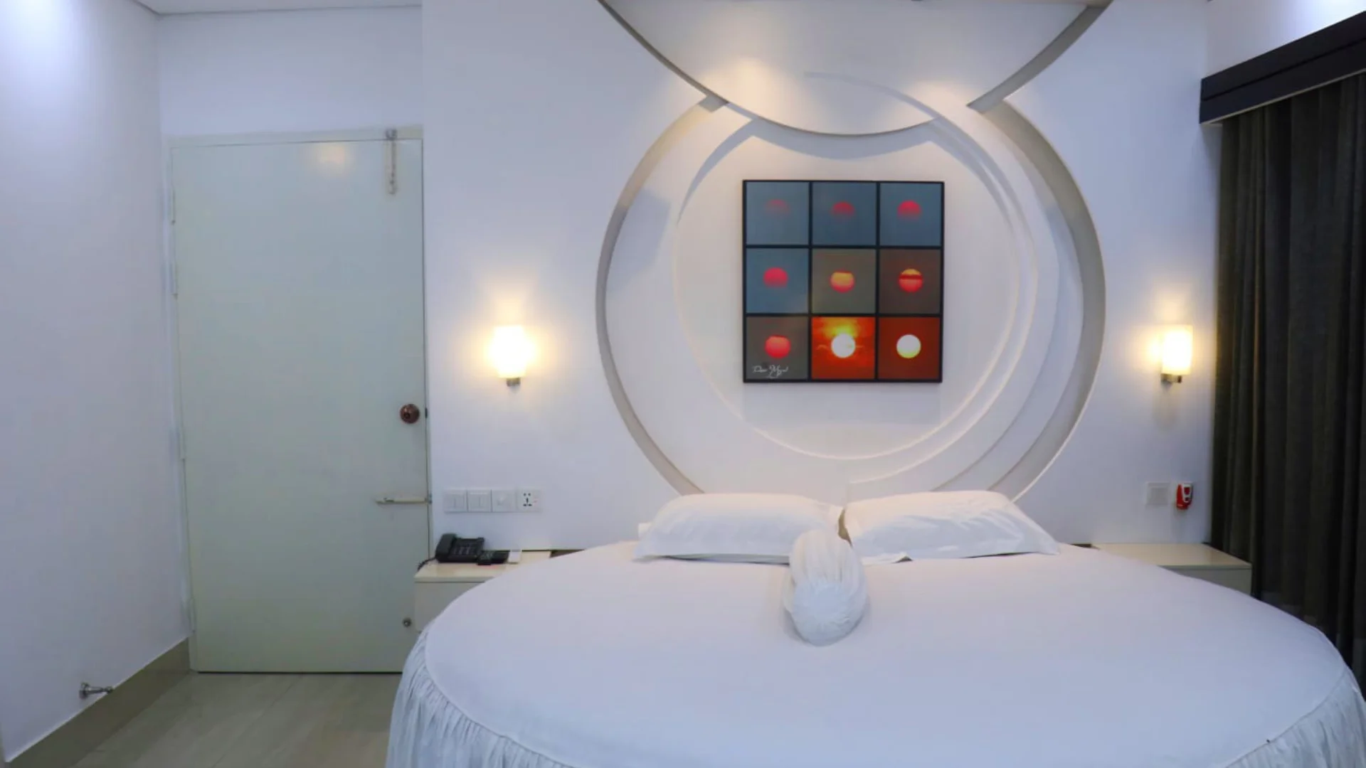 Sky Lawn Hotel guest room features a neatly made bed with white linens, a gray tufted headboard, ...