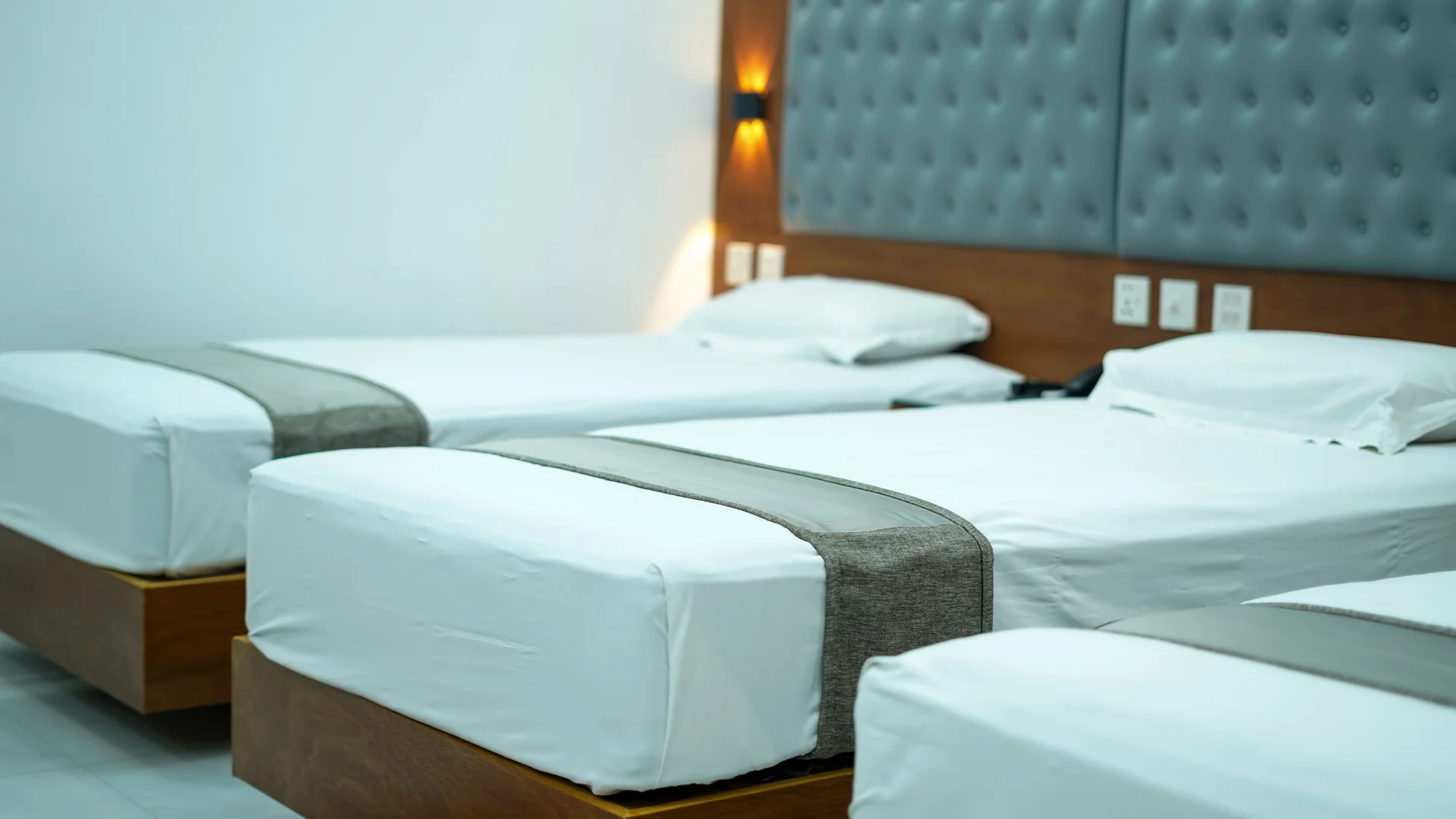 Sky Lawn Hotel's multi-bed guest room showcases a clean, modern aesthetic with crisp white linens...