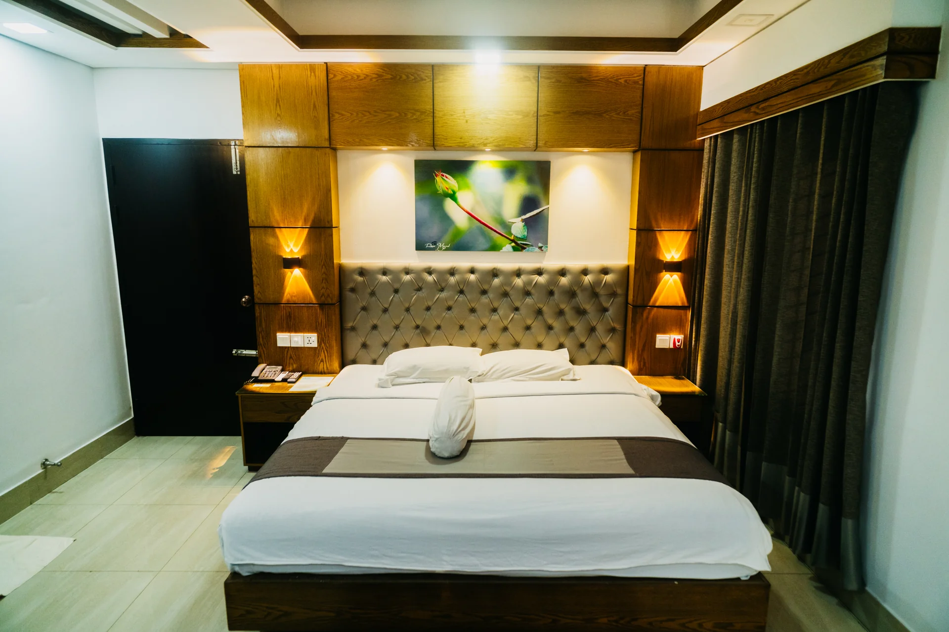 Sky Lawn Hotel guest room features a modern, elegantly designed space with a king-sized bed, tuft...