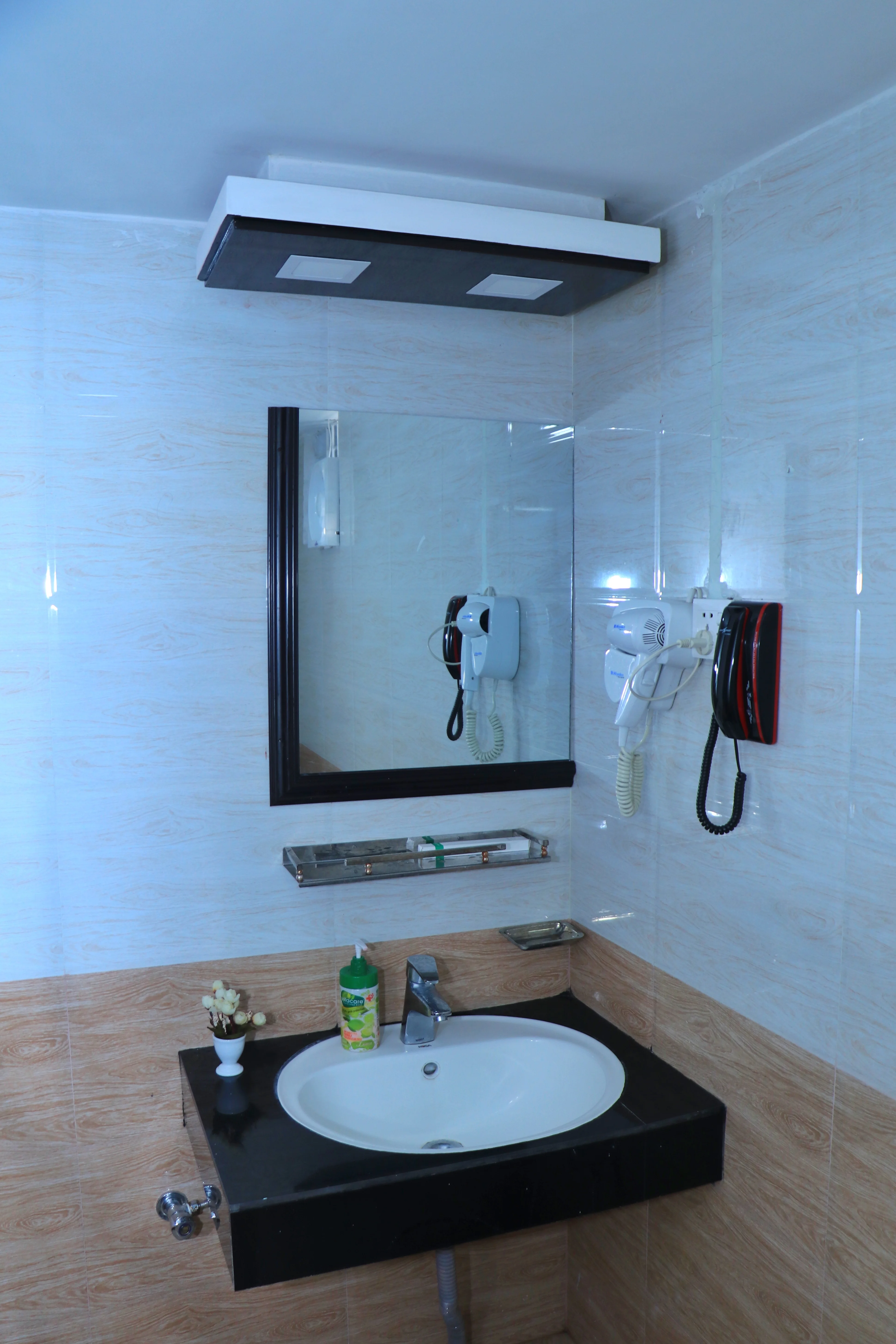 Sky Lawn Hotel's hotel bathroom features a modern design with a black countertop sink, a framed m...