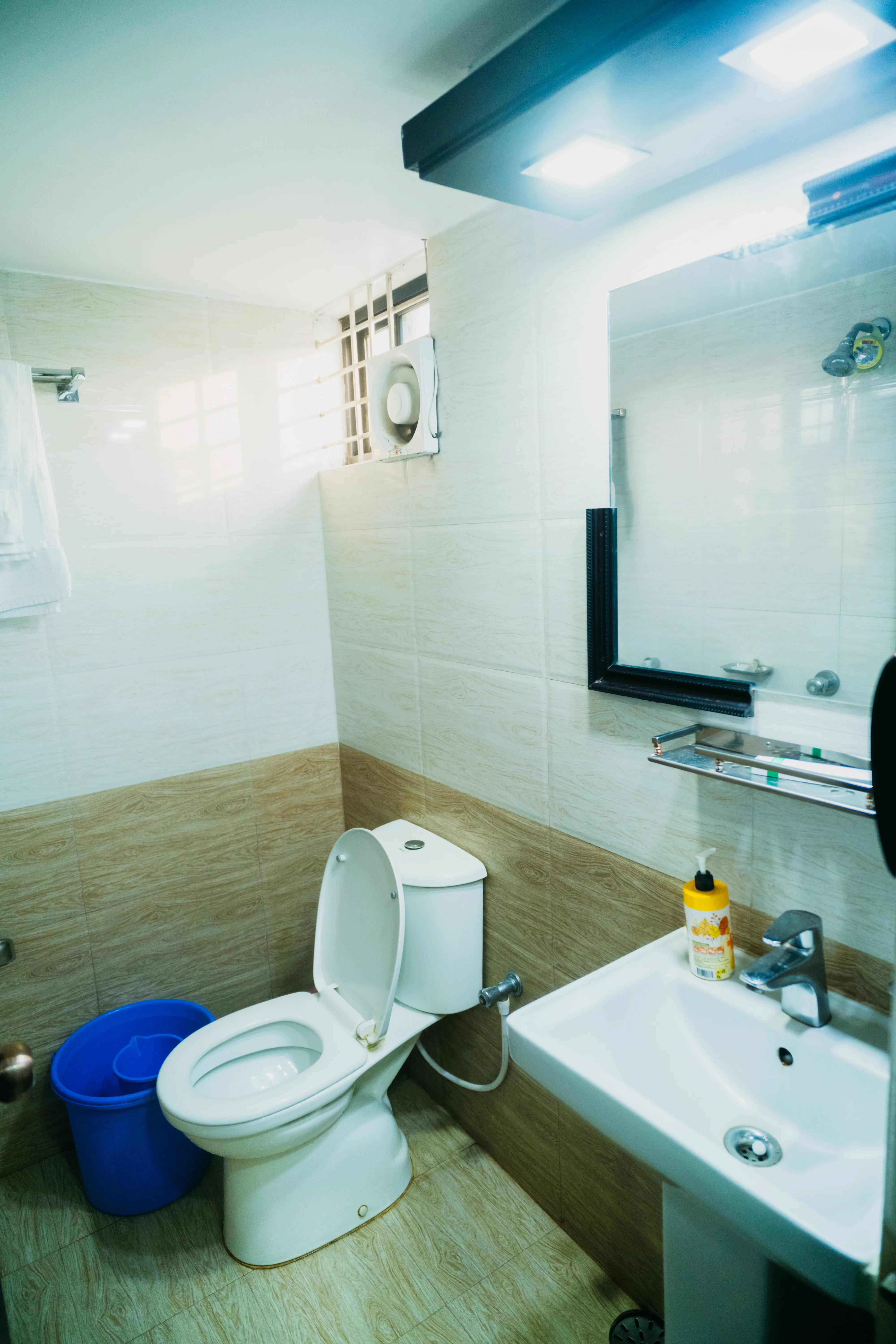 Sky Lawn Hotel's bathroom features a modern, accessible guest space with gray textured tile walls...