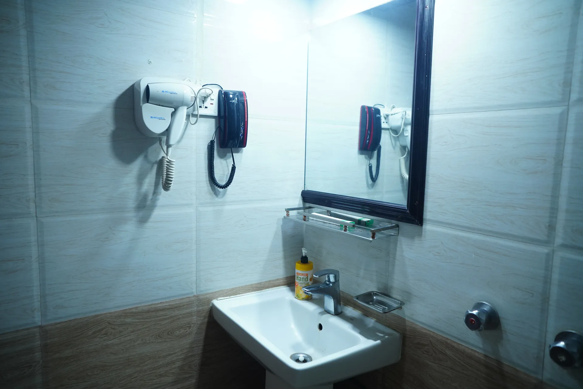 Sky Lawn Hotel’s guest bathroom features a modern design with light-toned tiled walls, wooden low...