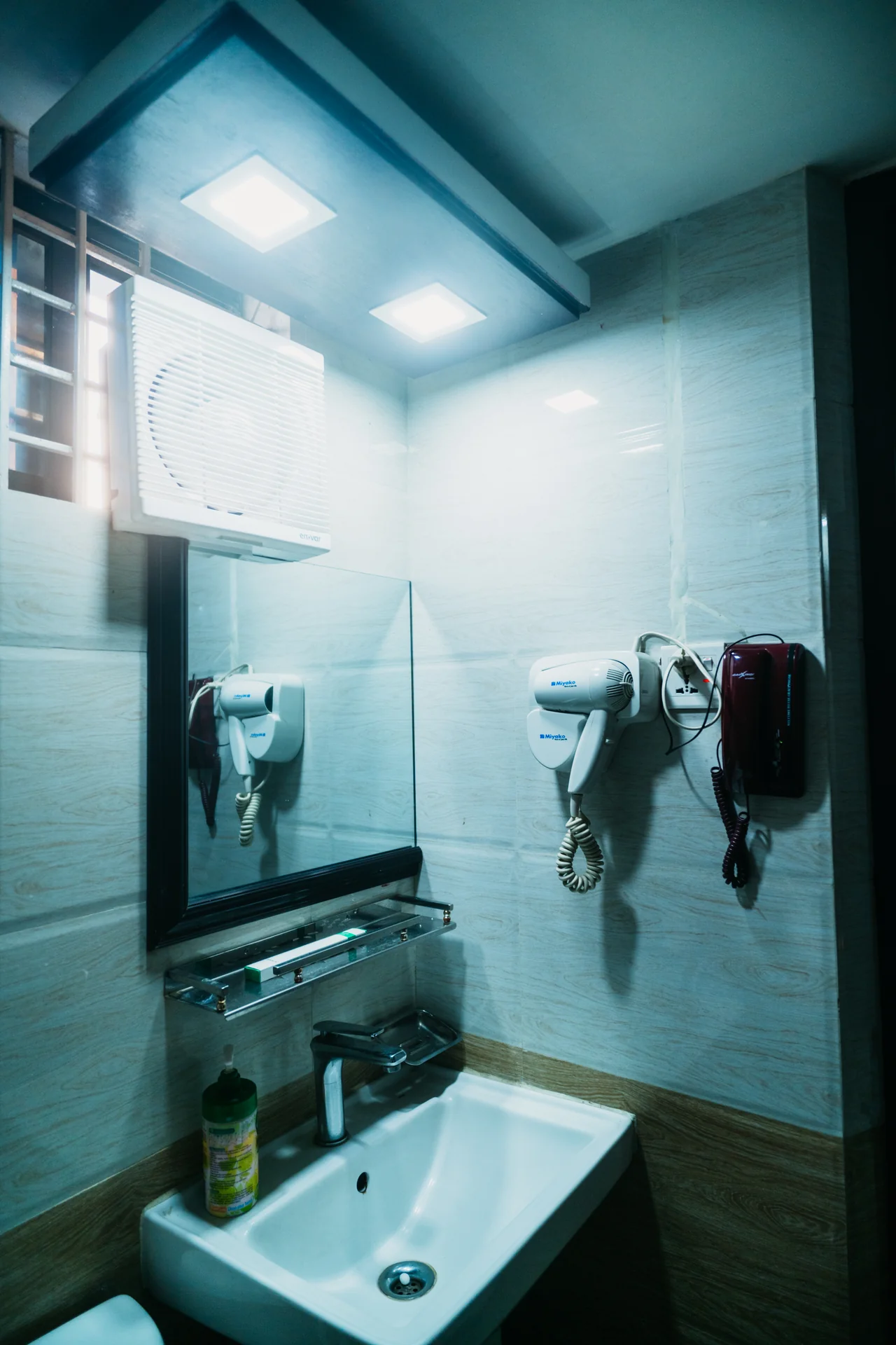 Sky Lawn Hotel's bathroom features a modern, accessible guest space with gray textured tile walls...