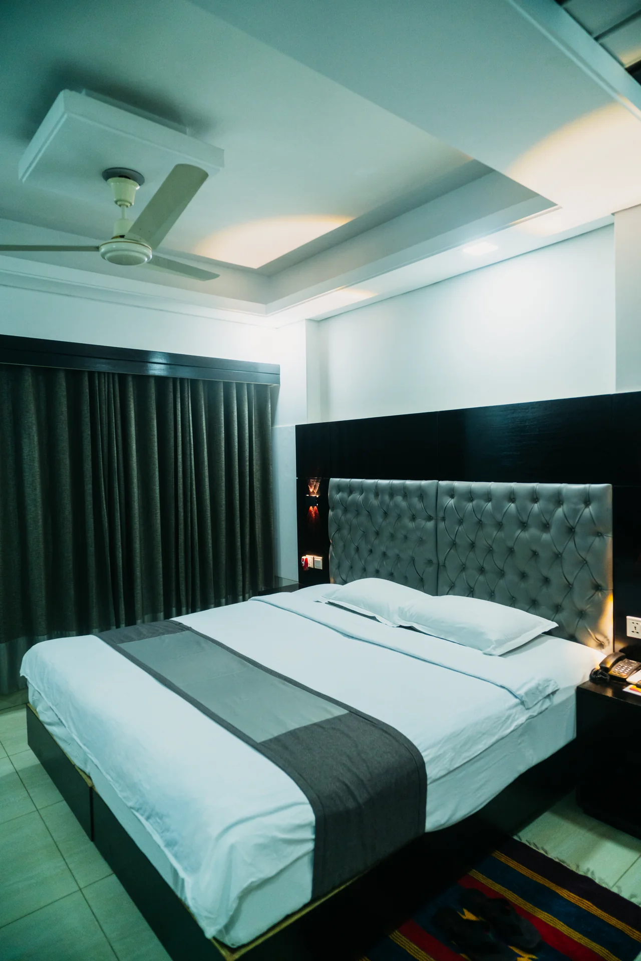 Sky Lawn Hotel guest room features a modern, elegantly designed space with a king-sized bed, tuft...