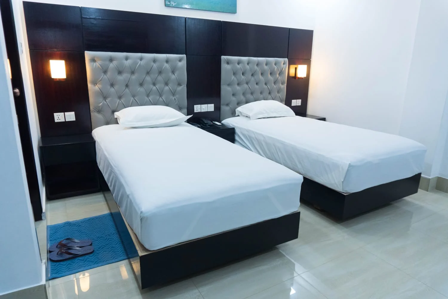 Sky Lawn Hotel's modern double guest room features two single beds with crisp white linens and pl...