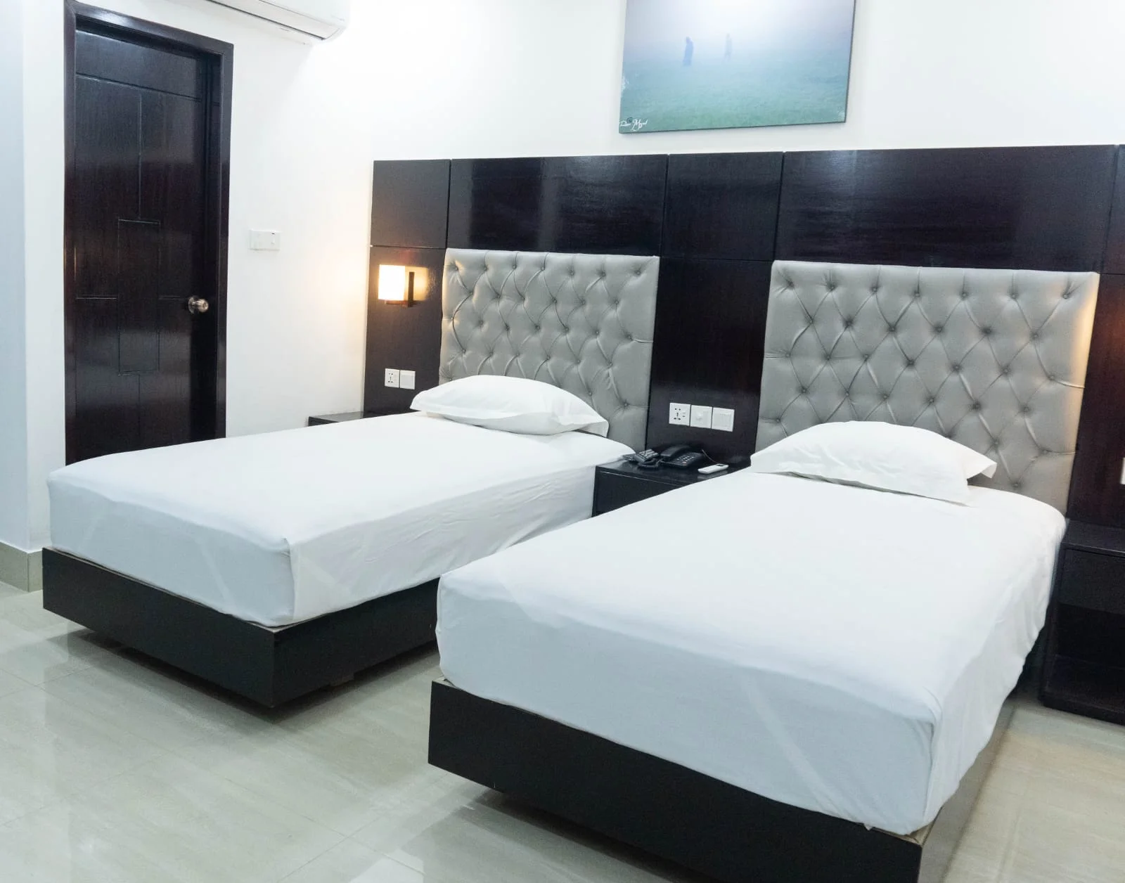Sky Lawn Hotel’s twin bedroom suite offers a modern, clean space with two single beds dressed in ...