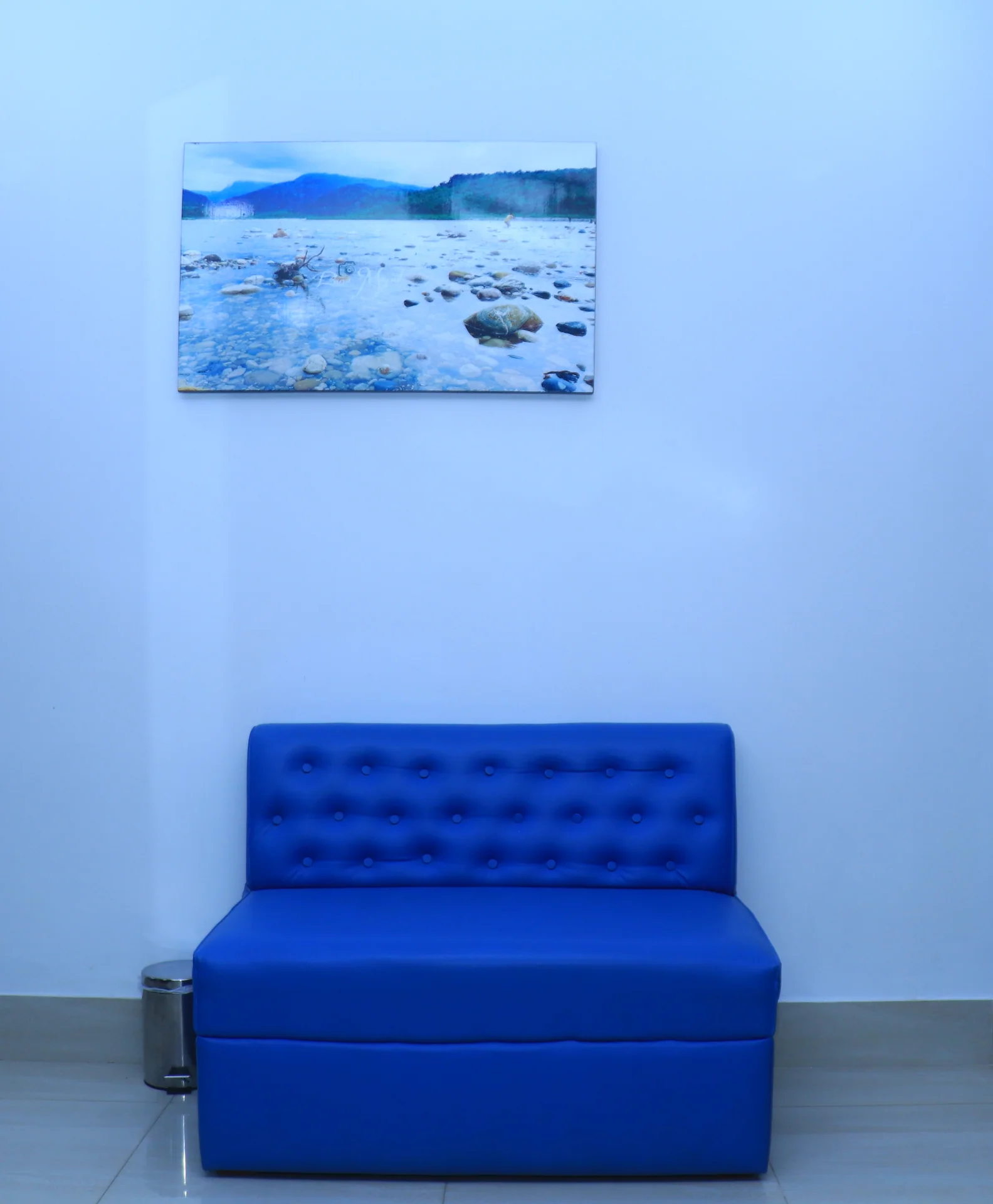 Sky Lawn Hotel’s lobby area features a vibrant blue tufted sofa, a serene lake landscape painting...