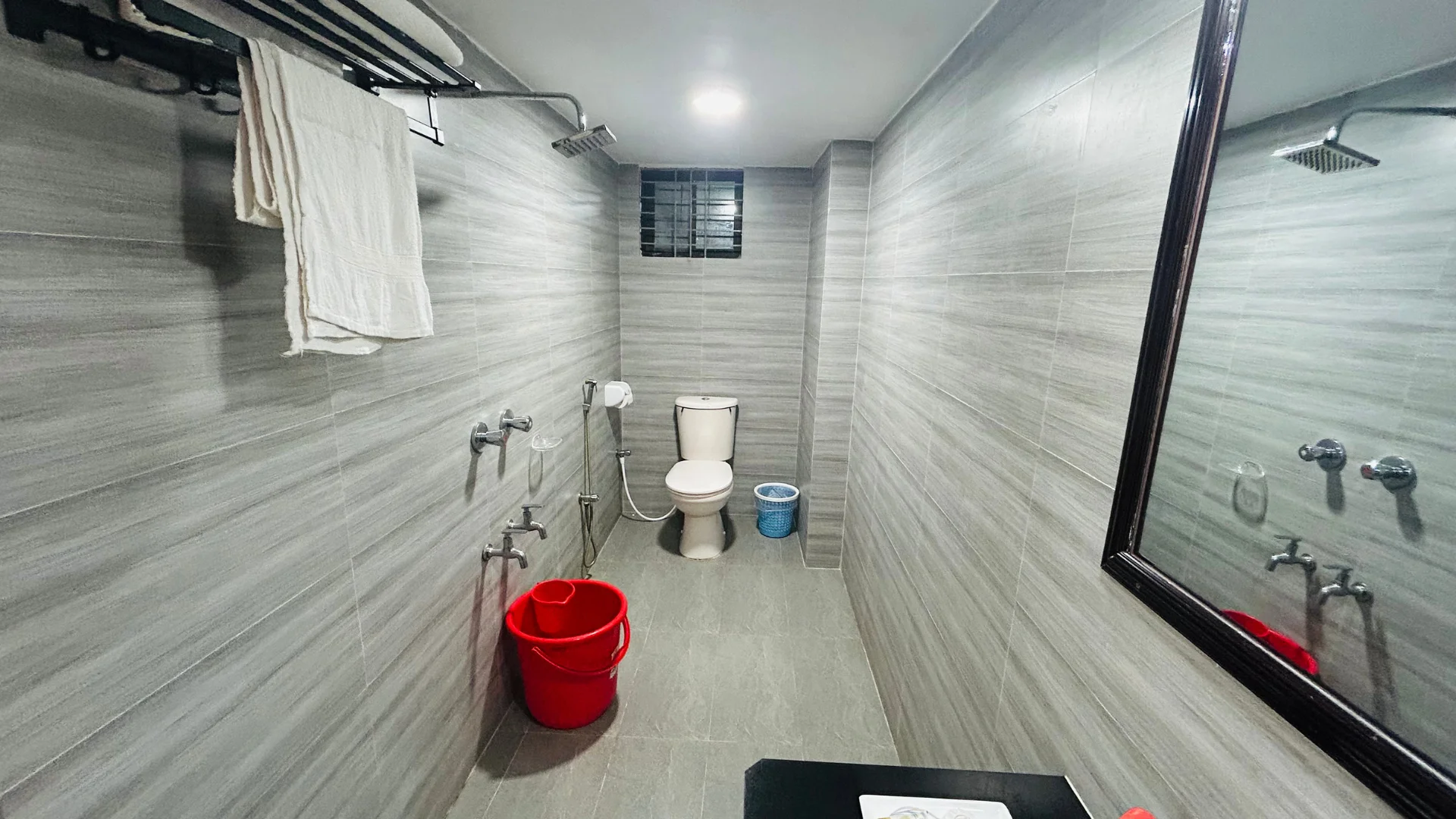 Sky Lawn Hotel’s guest bathroom features a modern design with light-toned tiled walls, wooden low...